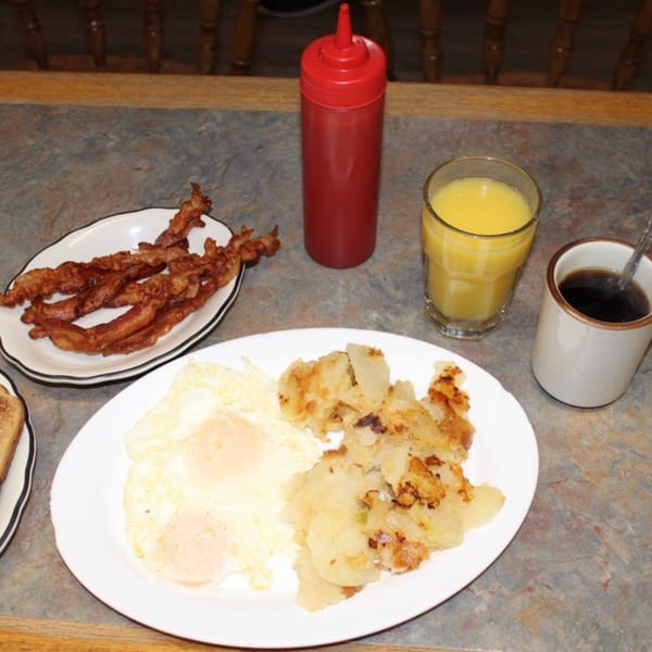 A classic American breakfast with fried eggs, hash browns, bacon, orange juice, and coffee.