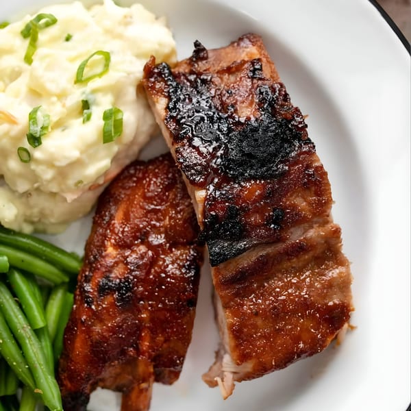Old Glory's BBQ ribs with mashed potatoes and green beans on a white plate.